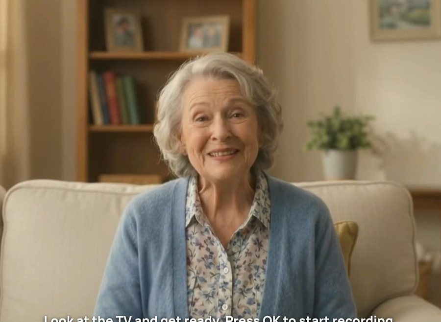 A smiling resident sitting on a sofa, looking at the TV